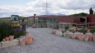 Baustelle des Kräutermarktes mit Pflanzentöpfen und Baugerüsten unter bewölktem Himmel