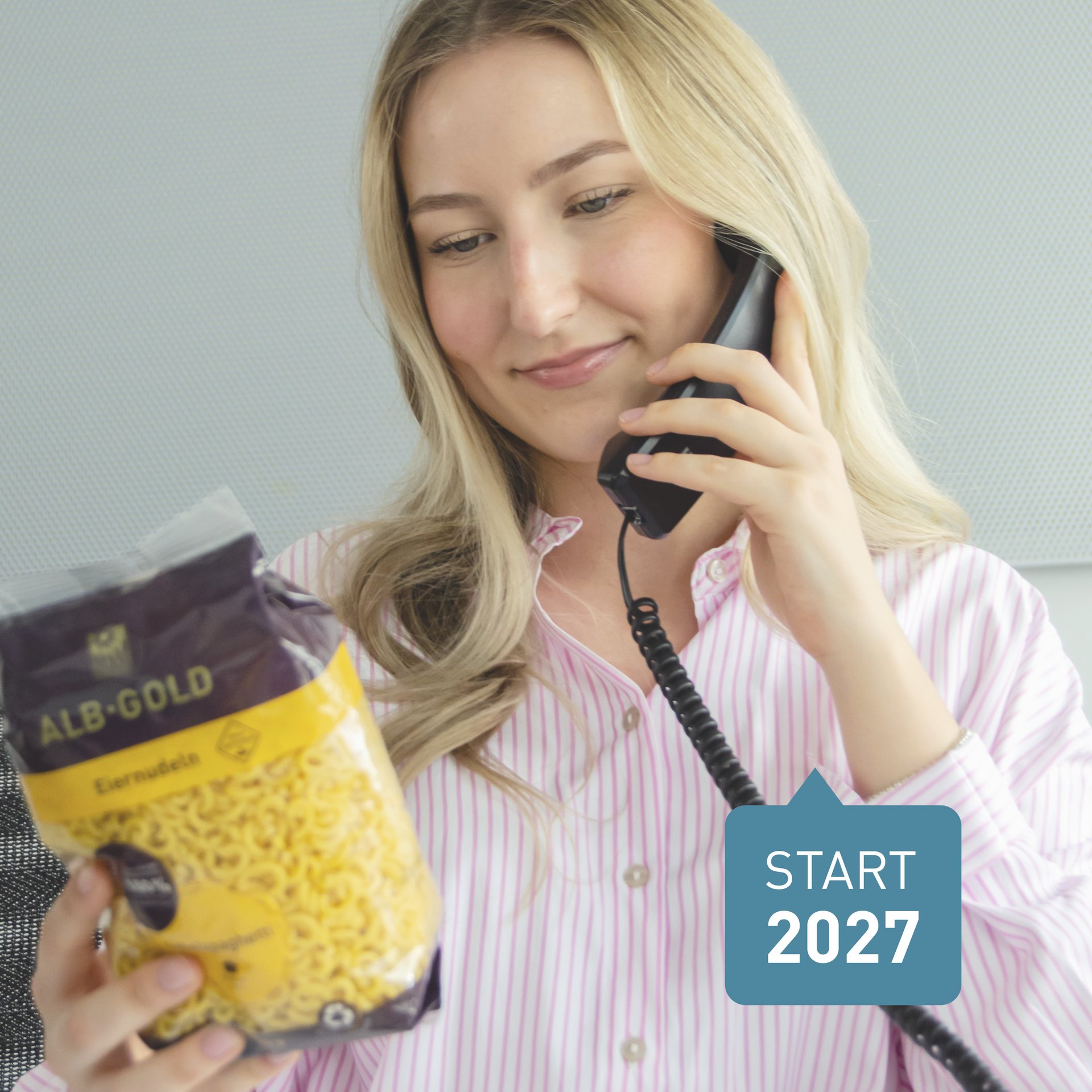 Frau mit blonden Haaren, die beim Telefonieren eine Packung Pasta hält.
