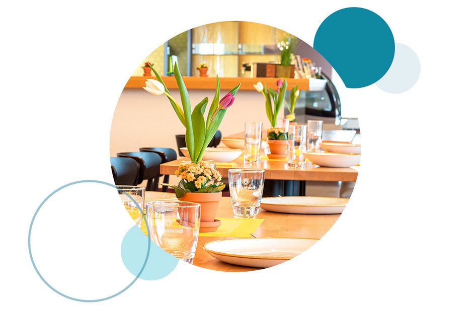 Tisch im Restaurant mit Gläsern, Tellern und Töpfen mit Tulpen als Dekoration