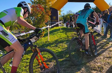Zwei Mountainbiker fahren auf einem sonnigen, hügeligen Waldweg bei einem Rennen