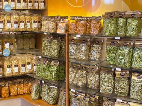 Regale mit verschiedenen getrockneten Nudeln und Hülsenfrüchten in durchsichtigen Verpackungen in einem Laden