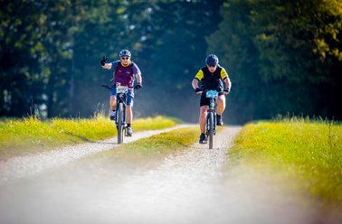 Zwei Trophy Teilnehmer auf einem Feldweg, umgeben von Wiese und Bäumen.