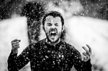 Mann im Schnee schreit mit geballten Fäusten, zeigt starke Emotionen