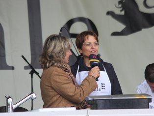 Zwei Frauen stehen auf einer Bühne und unterhalten sich mit einem Mikrofon in der Hand.