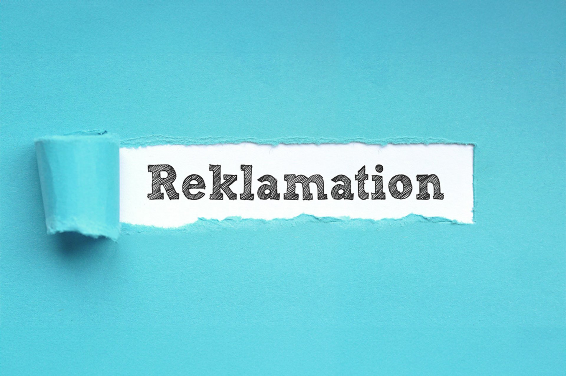 Das Wort 'Reklamation' auf einem weißen Papierstreifen vor blauem Hintergrund