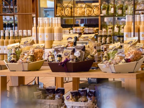 Tisch mit verschiedenen Produkten, darunter Flaschen mit gelbem Eierlikör und Körbe mit verpackten Lebensmitteln in einem Laden