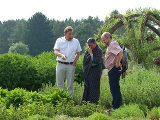 Drei Personen befinden sich im ALB-GOLD Naturgarten, eine Person erklärt den anderen beiden etwas über die Pflanzen.