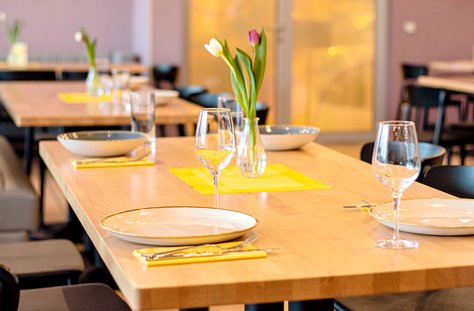 Modernes Restaurant mit Holztischen, schwarzen Stühlen und frischen Blumen auf den Tischen