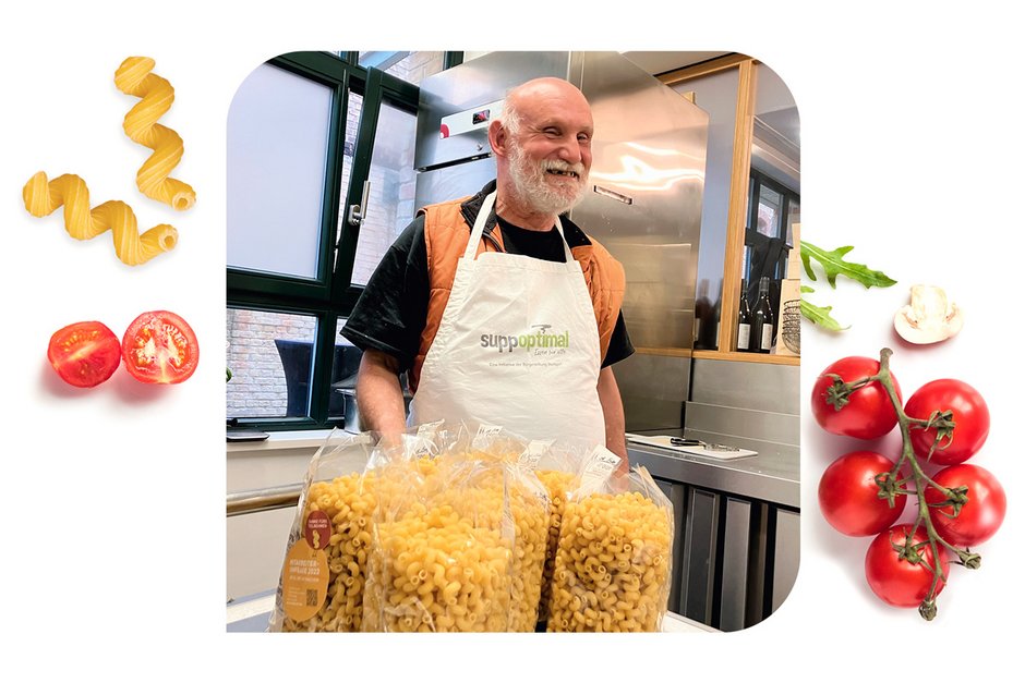 Ein Mann, der Pasta und frische Tomaten in der Küche präsentiert.