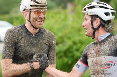 Zwei Radfahrer, die nach einem Wettkampf schmutzig und glücklich sind.