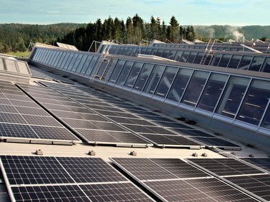 Solar panels installed on a rooftop with a forested landscape in the background