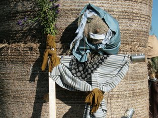  Kreative Vogelscheuche aus Stroh und Kleidung, die vor einem Strohballen steht.