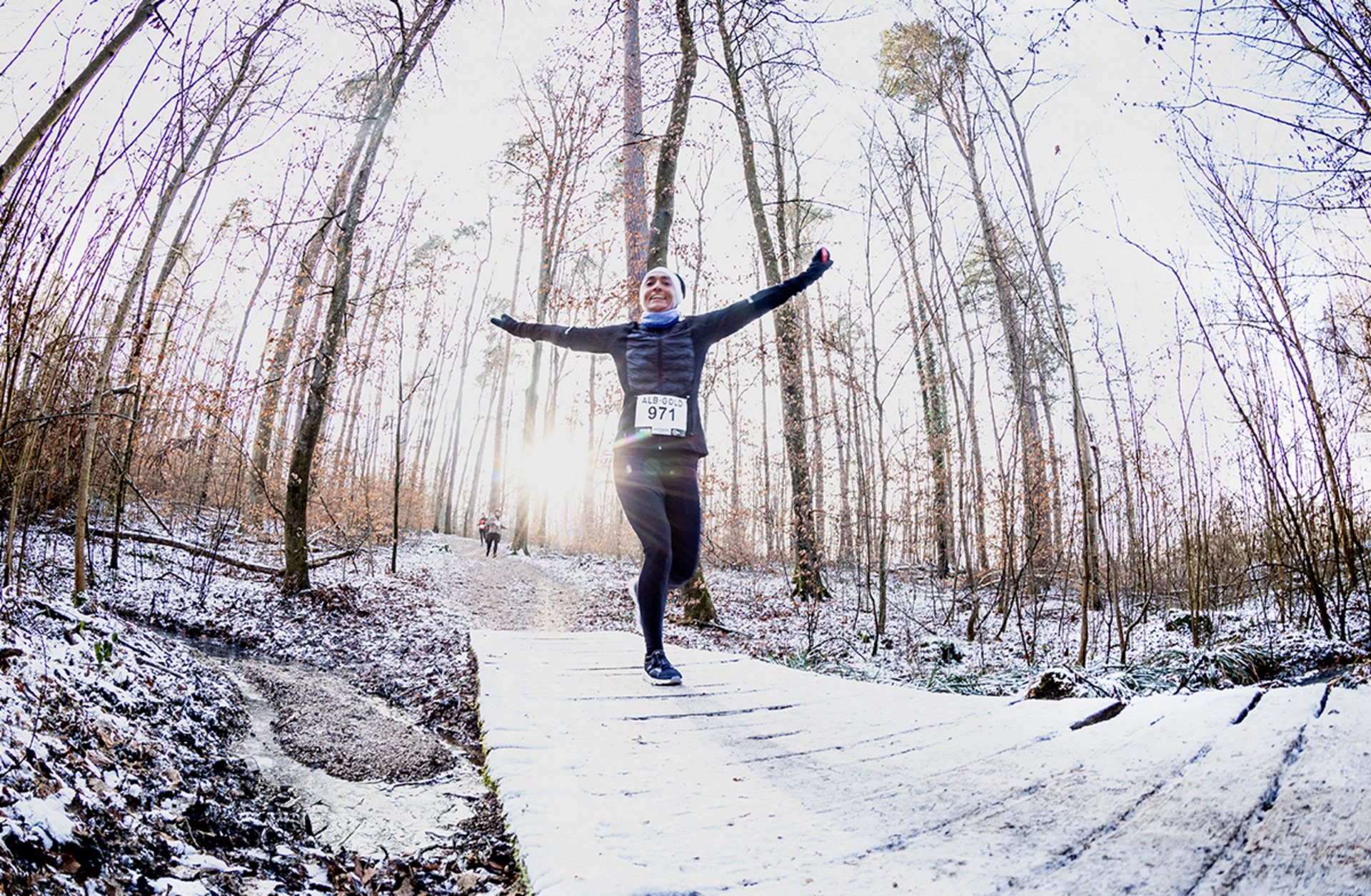 Winterlauf Läufer in einem mit Schnee bedecktem Waldweg.